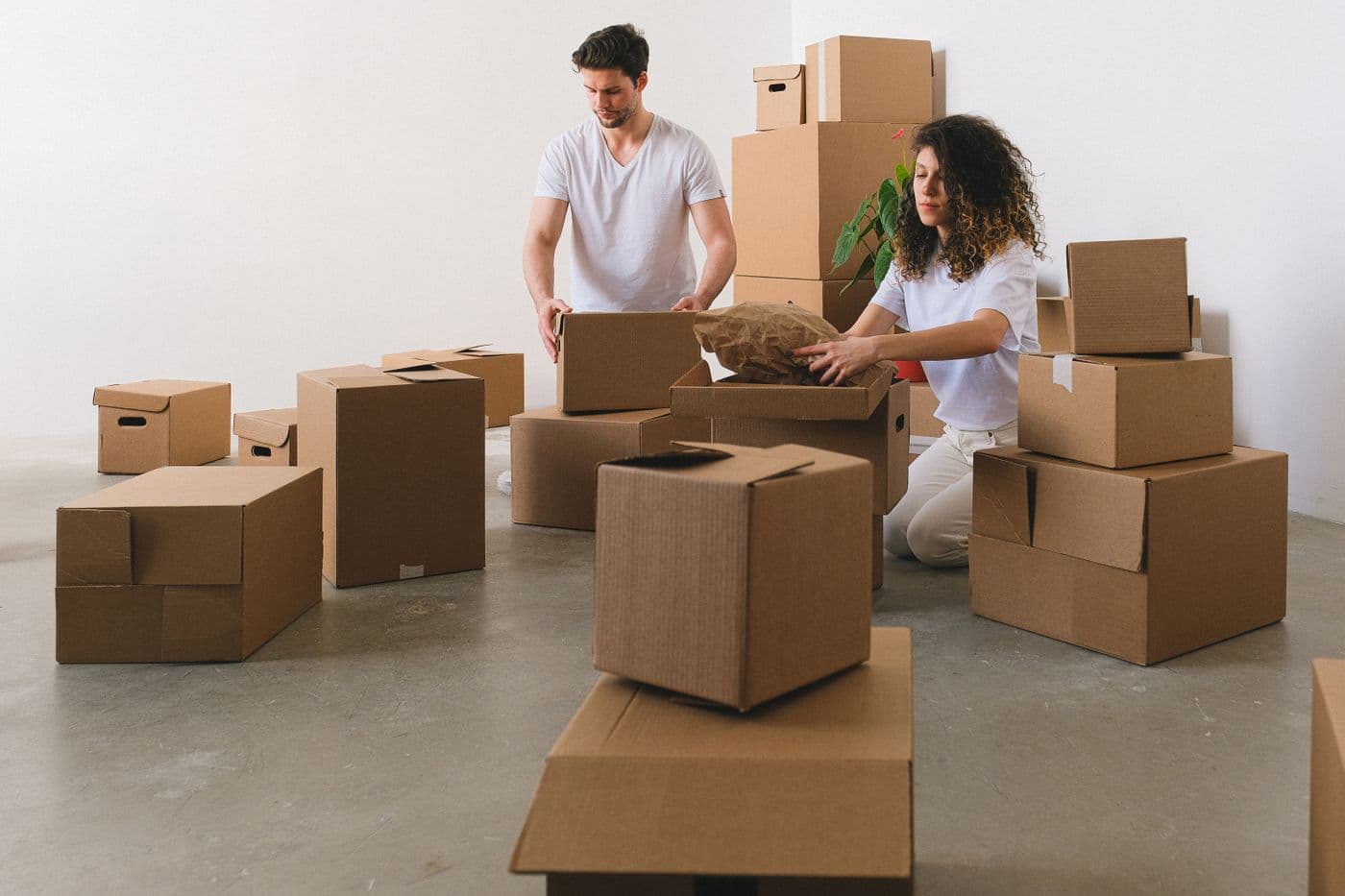 Two people packing belongings into cardboard boxes