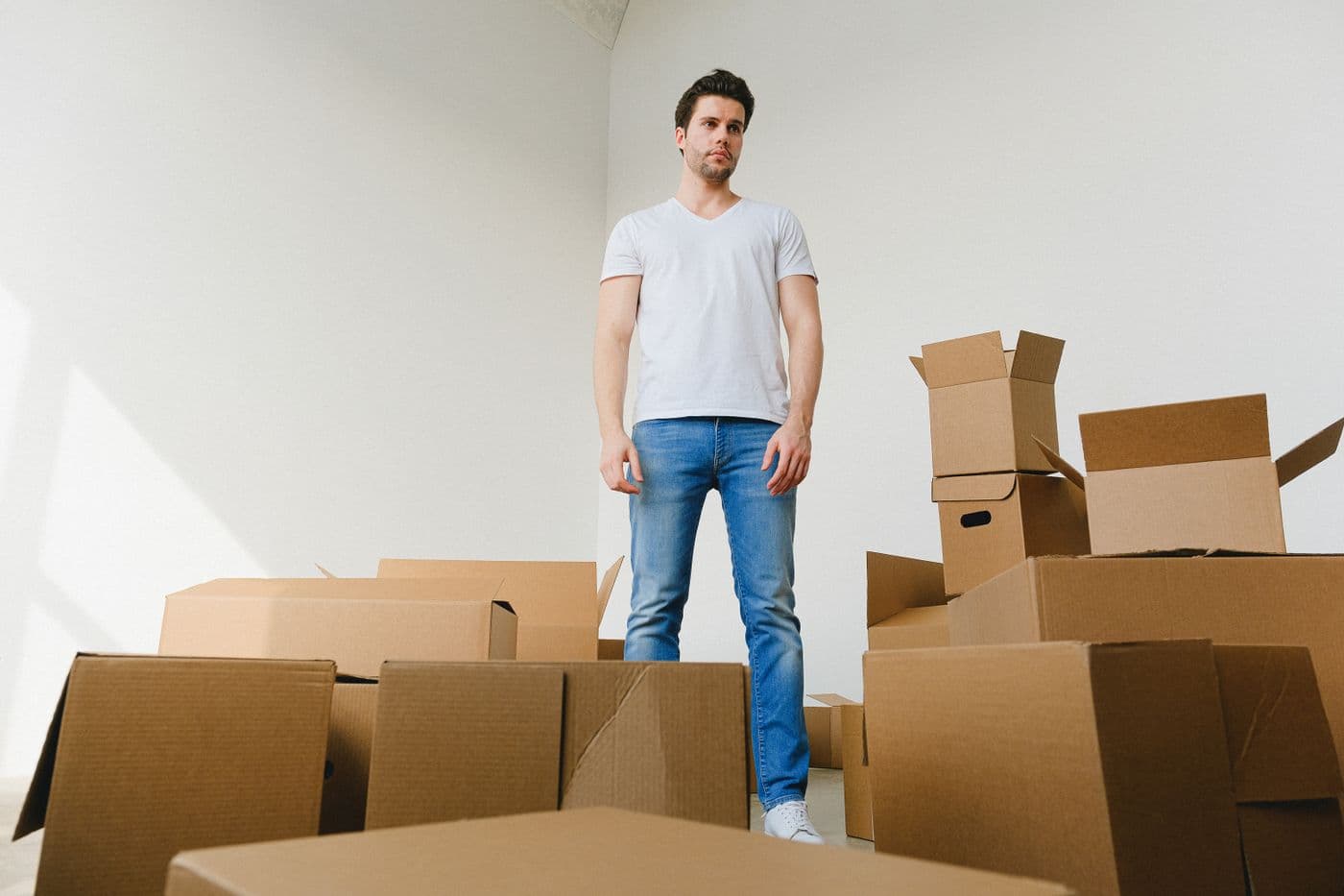 A person standing among packed and open cardboard moving boxes